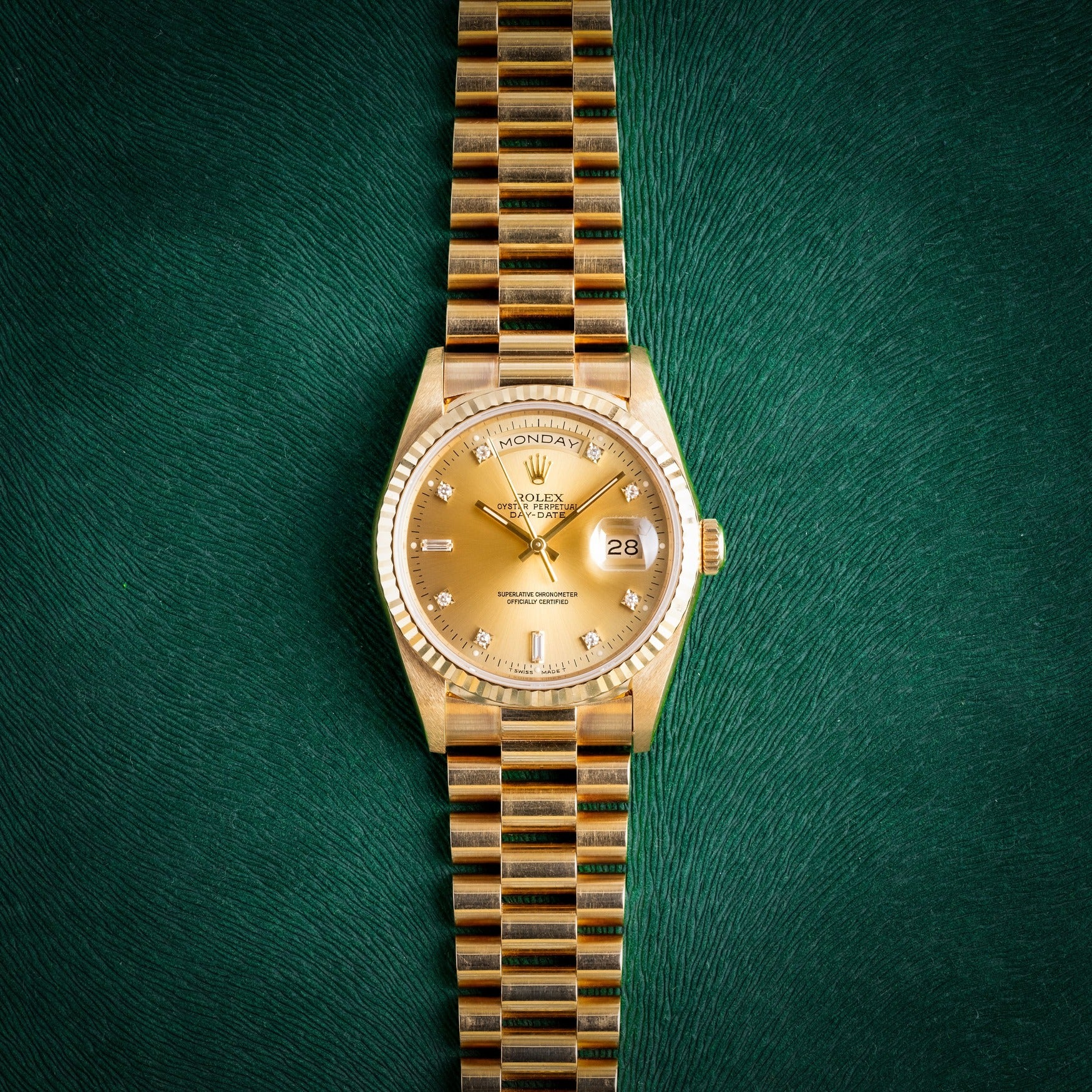 Goldene Rolex Day-Date Luxusuhr auf strukturiertem grünem Hintergrund